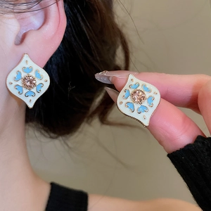 Close-up of diamond-set heart earrings with enamel finish and pink gemstone
