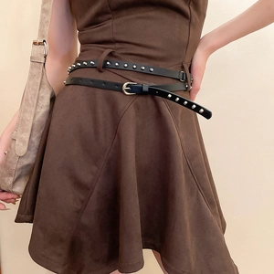 Détail de la ceinture noire à rivets argentés portée sur une robe en daim marron