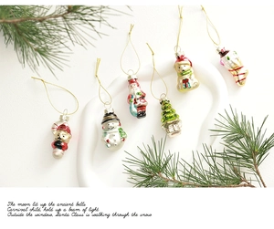 Detailed view of assorted glass Christmas ornaments including Santa and trees with pine branches