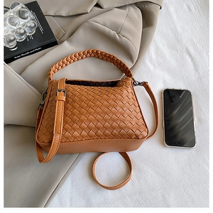 Close-up of caramel woven leather handbag with silver hardware and ring handles