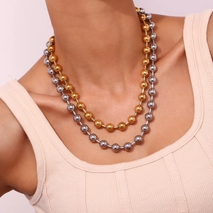 Détail de colliers à billes en or et argent portés par un mannequin de mode élégant