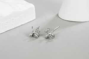 Detailed macro view of polished silver balloon dog stud earrings on a grey background
