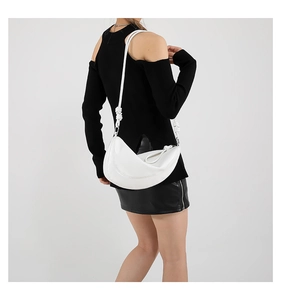 Close-up of white crescent shoulder bag with knot detail and silver metal hardware
