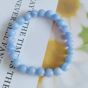 Macro detail of 8mm blue cat eye stone beads with natural striped texture on a card