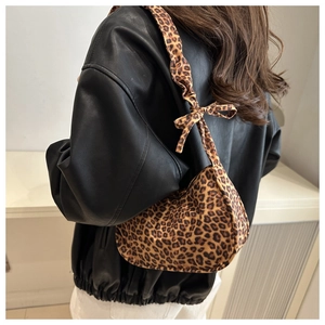 Detail of leopard print crossbody bag featuring ruffled shoulder strap and bow tied design