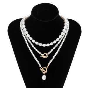Close-up of triple-layered pearl necklace with golden heart pendant on black bust display