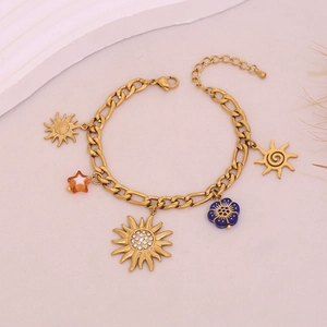 Gold chain bracelet with sun and flower pendants featuring crystals on beige background