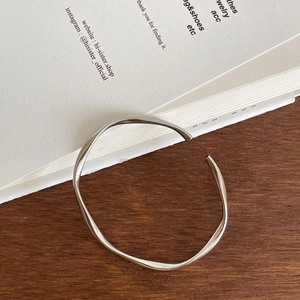 Macro detail of silver S925 mobius twist bangle with polished finish on wooden desk