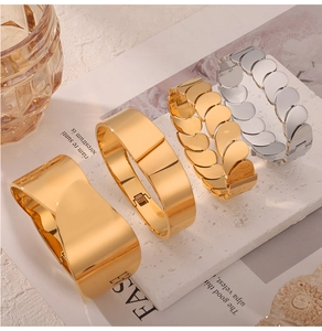Polished titanium steel bangles in gold and silver finish on a white stone pedestal