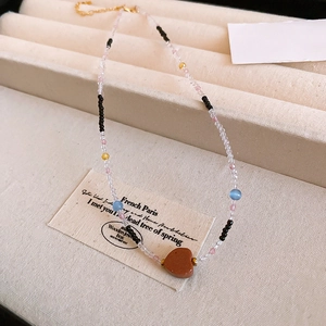 Macro detail of agate pearl necklace featuring a brown heart pendant and colorful beads