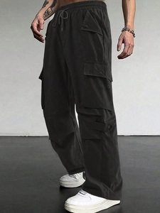 Detail of black techwear cargo pants featuring elastic drawstring waist and tactical pockets