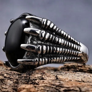 Macro detail of gothic dragon claw ring featuring a large black gemstone on rustic wood