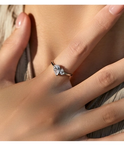 Macro detail of a silver ring featuring dual pear-cut clear stones on a hand