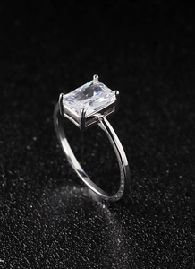 Macro shot of silver ring with large rectangular cut zircon on textured black background