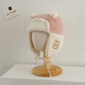 Detailed view of pink corduroy winter hat for babies with bear embroidery and earflaps
