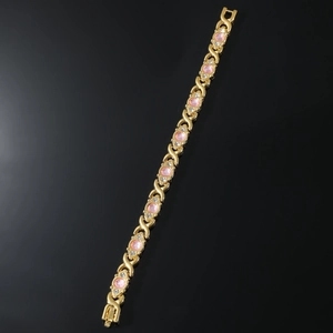 Close-up of gold magnetic bracelet with pink gemstones and clear crystals on black background