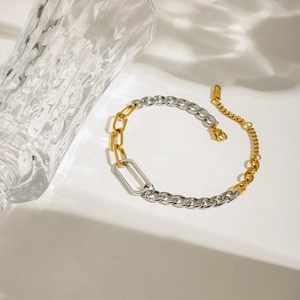 Modernes minimalistisches Armband aus Gold und Silber Mix auf einem cremefarbenen Grund