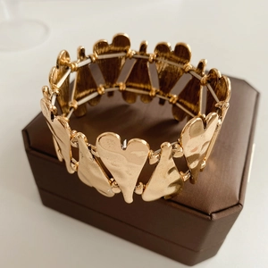 Gros plan du bracelet élastique cœur doré avec texture martelée sur une boîte à bijoux