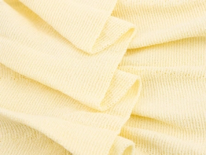Detailed macro view of soft pale yellow knitted fabric texture with pleated details