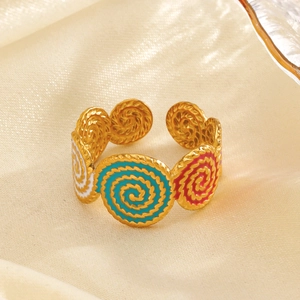 Golden stainless steel spiral ring with colorful enamel inlay on beige silk background