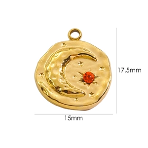 Macro detail of a 17.5mm gold celestial pendant with moon, star, and red crystal