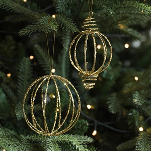 Boules de Noël pailletées dorées et pendentifs spirale sur un sapin de Noël vert