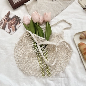 Vue détaillée du sac filet tissé crème en coton avec des tulipes roses à l'intérieur