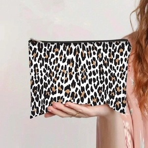 Close-up of leopard print canvas makeup bag with silver zipper held by a model
