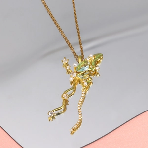 Gros plan du pendentif lézard doré avec pierre verte et perles blanches sur miroir