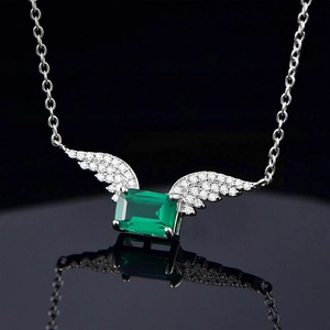 S925 silver necklace with emerald cut green gemstone and angel wings on black mirror