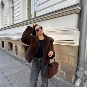 Brown fluffy faux fur cropped jacket with lapels styled with grey jeans in a city setting