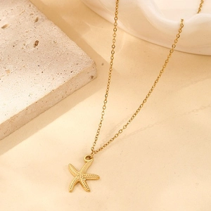 Close-up of golden starfish necklace with textured surface on minimalist stone background