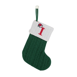 Detail of dark green cable knit Christmas stocking with white cuff and red letter I embroidery