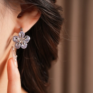 Gros plan d'un mannequin portant la boucle d'oreille fleur en zircon violet raffinée