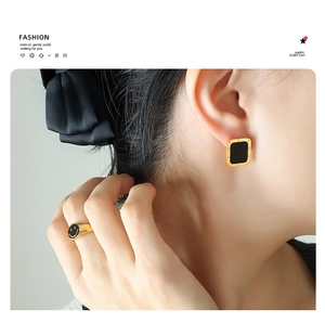 Close-up of gold rectangular roman numeral earrings and matching smiley face ring