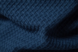 Close-up of deep blue waffle knit texture on a men's sweater showing detailed fabric weave