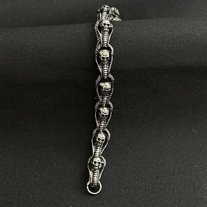 Detailed view of silver skull link chain bracelet in punk style on a black background