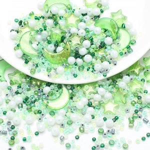Close-up of green and white moon and star beads in a ceramic tray for DIY jewelry making