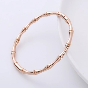 Detailed view of a rose gold bamboo style stainless steel bangle on white background