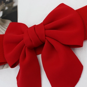 Women's red elastic waist belt featuring a large decorative 3D bow on white background