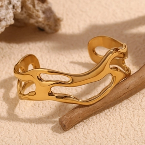 Close-up of a minimalist 18K gold-plated stainless steel hollow wavy bangle on a textured surface