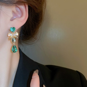 Gros plan de boucles d'oreilles pendantes avec pierres vertes en forme de cœur et goutte