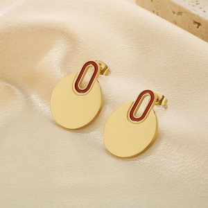 Detailed shot of golden circular drop earrings with red enamel detail on satin silk