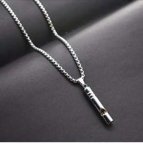 Close-up of a silver metal whistle pendant necklace on a bead chain with high metallic luster