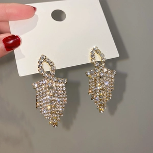 Detailed close-up of golden tassel earrings with sparkling rhinestones and geometric design