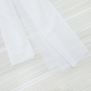 Detail of multi-layered white semi-transparent fabric strips on a light wood background