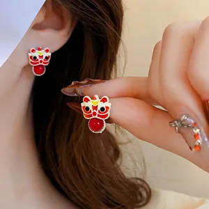 Festive lion dance earrings with red beads and enamel detail on model's ear
