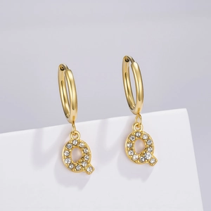 Macro detail of golden Q letter earring with pavé white cubic zirconia inlay