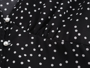 Detail of elegant black polka dot dress with pearl buttons and ruffled chest design