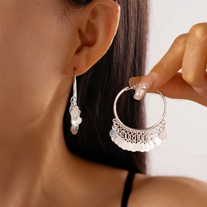 Detail of silver hoop earrings featuring multiple polished round sequins and a fringe effect